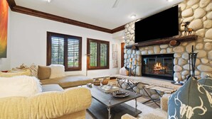 Una sala de estar acogedora con chimenea de piedra, asientos cómodos y un televisor de pantalla plana.