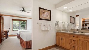 A hotel room with a large bed, a wooden vanity, and a ceiling fan. - The Charter at Beaver Creek C035 (Beaver Creek)