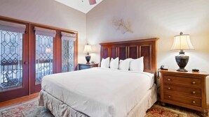 A bedroom with a large bed, wooden headboard, two bedside lamps, a nightstand, and a dresser. - The Charter at Beaver Creek B430 (Beaver Creek)
