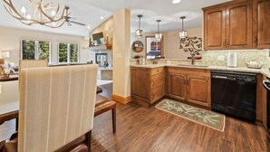 A modern kitchen with wooden cabinets, a dishwasher, and a chandelier.