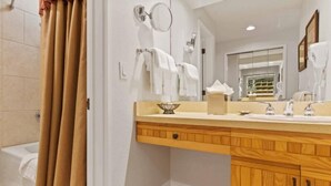 A bathroom with a wooden vanity, a large mirror, and a bathtub. - The Charter at Beaver Creek B335 (Beaver Creek)