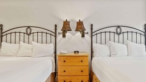 A double room with two beds, a wooden nightstand, and two wall-mounted lamps. - The Charter at Beaver Creek B335 (Beaver Creek)