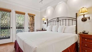 Une chambre à coucher avec un grand lit, une table de chevet, une lampe et une commode.