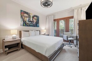Ein Hotelzimmer mit einem großen Bett, Nachttischlampen, einem Schreibtisch mit Stuhl, einem Bild an der Wand und Blick durch das Fenster.