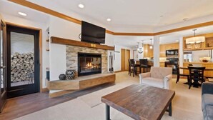 A modern living room with a fireplace, a dining area, and a kitchen. - The Charter at Beaver Creek B230 (Beaver Creek)