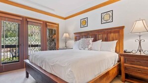 A bedroom with a wooden bed, two bedside tables, a nightstand, and a window with a view. - The Charter at Beaver Creek B230 (Beaver Creek)