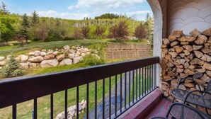 A balcony with a view of a landscaped garden, a stack of firewood, and a wooden fence. - The Charter at Beaver Creek B230 (Beaver Creek)