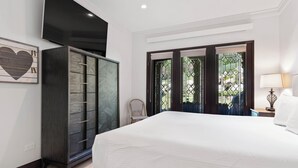 Una camera da letto con un letto grande, un armadio, una sedia e una finestra vista verde.