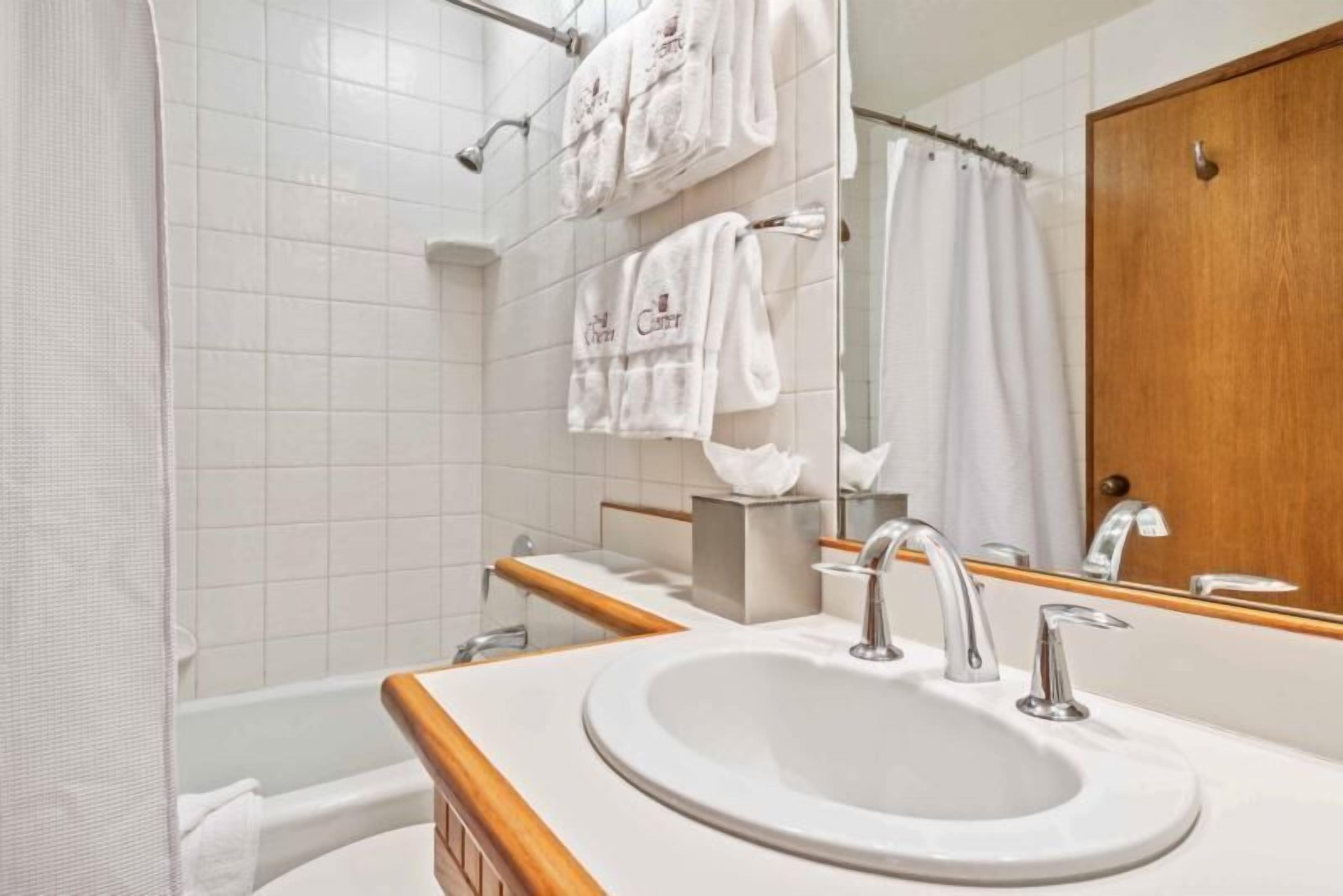 A bathroom with a white sink, two faucets, a mirror, and a shower curtain.