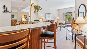 Une cuisine moderne dotée d’un îlot central aux lignes courbes, de chaises en bois et d’un coin repas comprenant un canapé et une table.