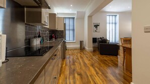 A modern kitchen with a black countertop, stainless steel appliances, and a wooden floor. - Inviting 1-bed Apartment in Lytham Saint Annes (Lytham St. Anne's)