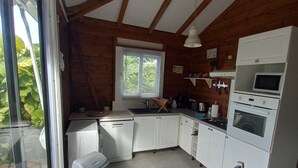 Una cocina con armarios blancos, un microondas, un horno, un fregadero y una ventana con persianas.