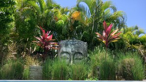 Una piscina rodeada de exuberante vegetación tropical y una escultura de piedra.