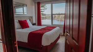 A bedroom with a large bed, a window with a view of a lake, and a mirror on the wall. - Auberge Lac du Pin Rouge (Saint-Hippolyte)
