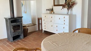 Um quarto aconchegante com lareira, cômoda branca, espelho e cadeiras de vime.