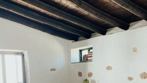 Quarto com cama, mesa de cabeceira, mesinha e janela.