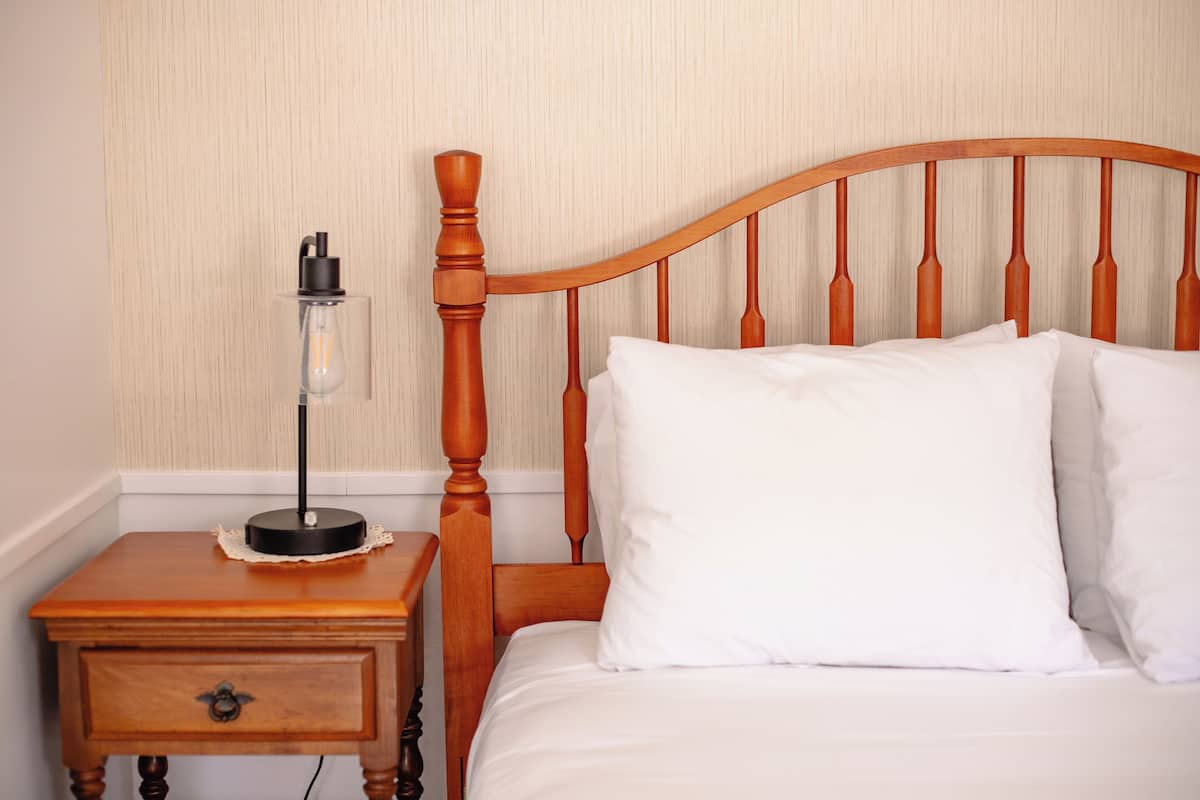 Una cama bien hecha con sábanas blancas y cabecera de madera.