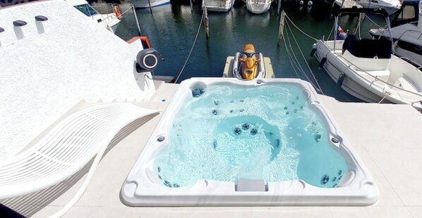 Una vasca idromassaggio sul ponte di una barca, con vista su altre imbarcazioni nel porto turistico.