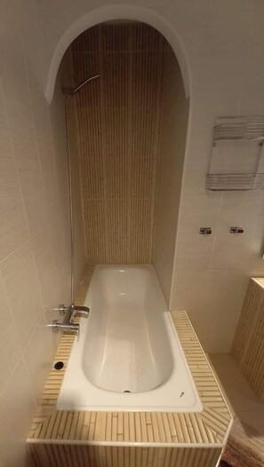 Un bagno moderno con una vasca freestanding, un mobile lavabo in legno a doghe e un portasciugamani a parete.
