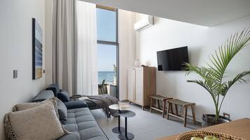 Een moderne woonkamer met een bank, een salontafel en een aan de muur bevestigde televisie.