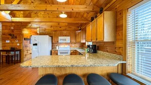 L’intérieur d’un chalet en bois comprend une cuisine, des tabourets de bar et un coin repas.