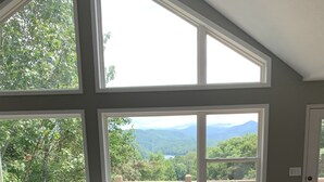 A spacious living room with a large gray sectional sofa, a coffee table, and a view of mountains and trees through large windows. - Amazing view from the Family Lake Retreat (Murphy)