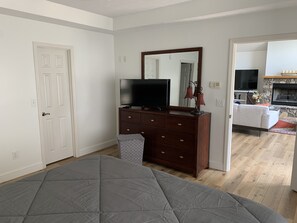 Un dormitorio con cama, cómoda con televisor, espejo y puerta.