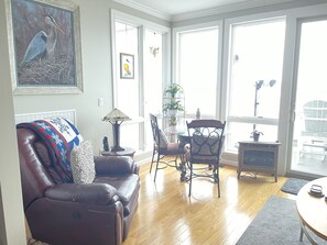 Una sala de estar con sofá de cuero, una mesa de centro, chimenea y ventanas amplias con vistas.