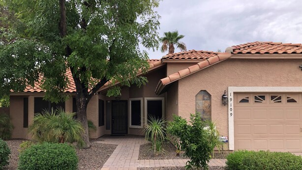 A residential building with a tiled roof, a garage, and a paved driveway leading to the entrance. - North Phoenix Close to Everything/ Secured Parking (Glendale)