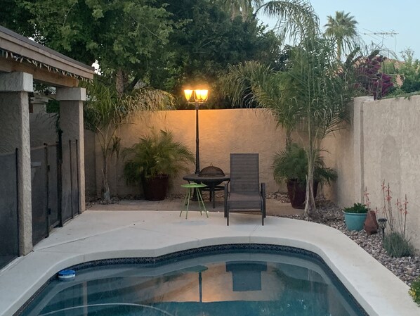 Relax by the pool surrounded by lush greenery and a low stone wall.