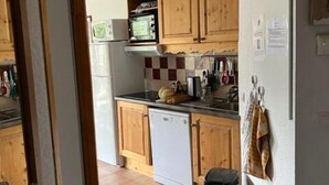 Una cucina compatta con mobili in legno, forno a microonde, lavastoviglie e schienale piastrellato.