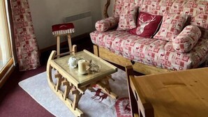 Un soggiorno accogliente con un divano a motivi, un piccolo tavolino con una lampada e una finestra con tende.