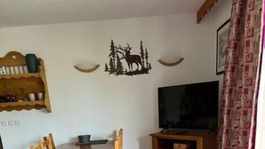Un accogliente soggiorno con un tavolo da pranzo in legno, sedie, una TV e un elemento decorativo a parete.