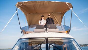 A boat with a canopy, two people on deck, and a clear view of the water.