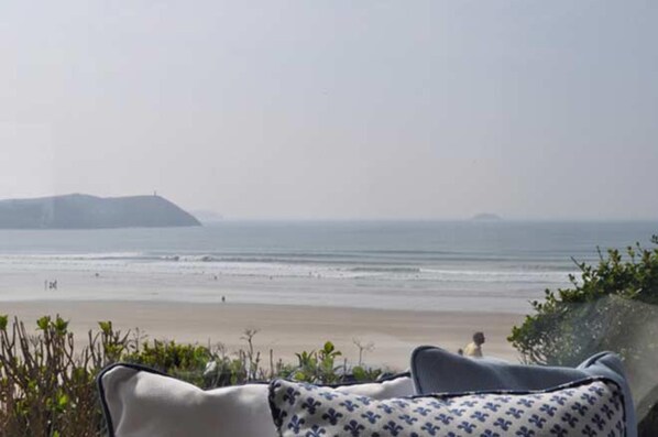 A beach view with a chair and a blanket, a sandy beach, and distant hills.