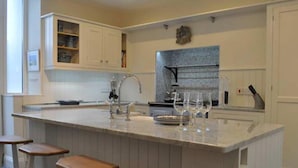 Eine Küche mit einer zentralen Kochinsel, Barhocker, Backofen und einer Spritzschutzwand.