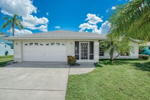 A single-story house with a garage, a small front yard, and a palm tree.