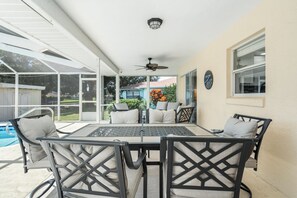 An outdoor patio with a table and chairs, a ceiling fan, and a view of a swimming pool and neighboring houses. - Welcome to Floridays...a quiet place by the lake (Lake Placid)