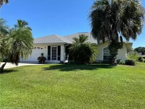 A single-story house with a well-maintained lawn and palm trees. - Welcome to Floridays...a quiet place by the lake (Lake Placid)