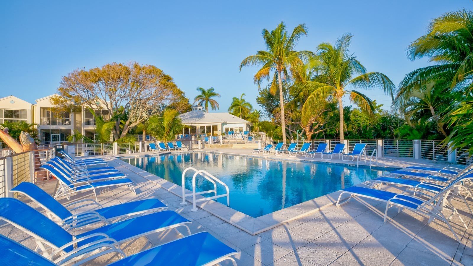 A pool area with blue lounge chairs and a clear blue pool.