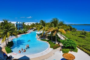 Piscina de resort con palmeras y vista al océano.
