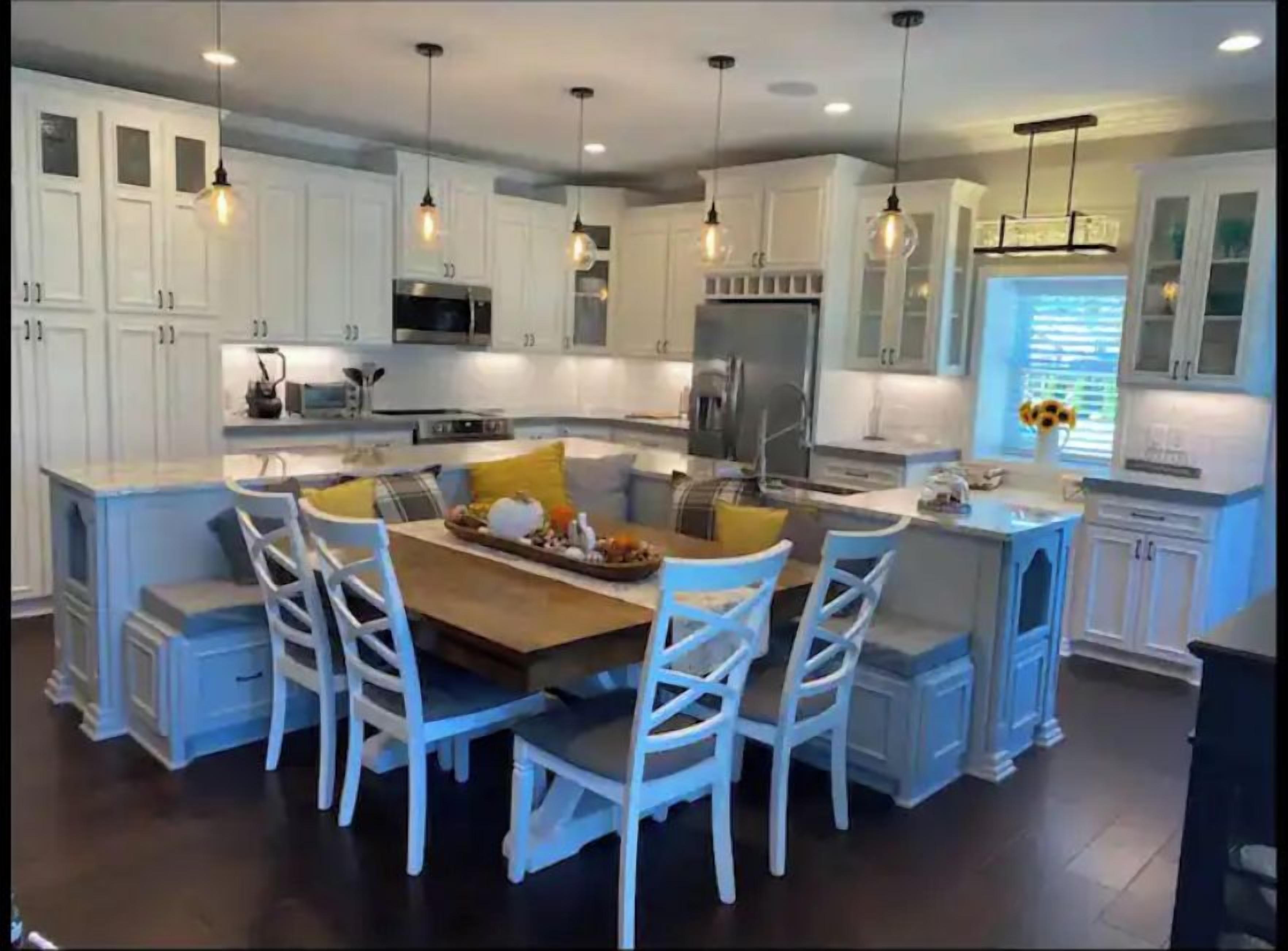 A modern kitchen with white cabinetry, a central island with seating, and pendant lighting.