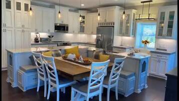 A modern kitchen with white cabinetry, a central island with seating, and pendant lighting.
