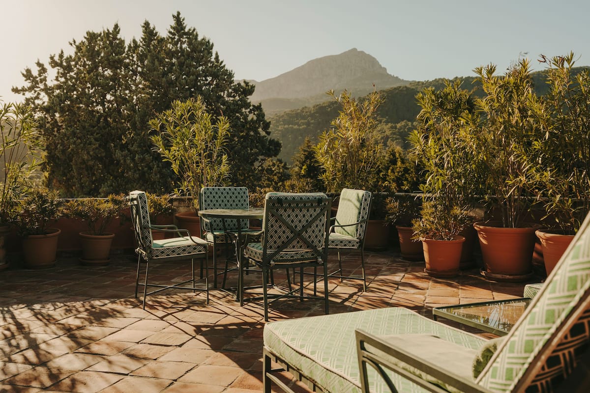 A patio with outdoor furniture, potted plants, and a view of a mountain.
