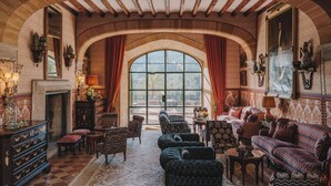 Una habitación amplia con un gran ventanal de arco, muebles ornamentales y una chimenea.