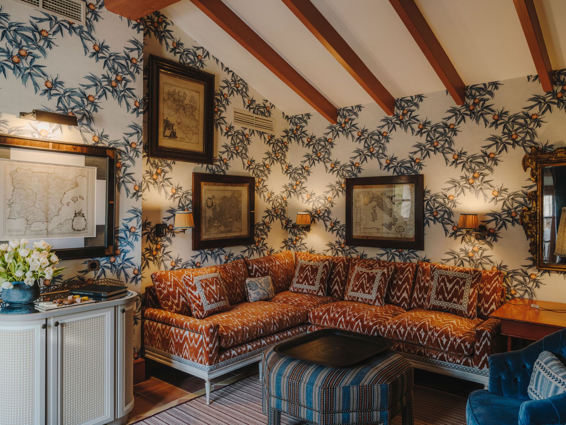Une pièce avec un mur orné de motifs, un canapé, une table basse et des cartes encadrées.