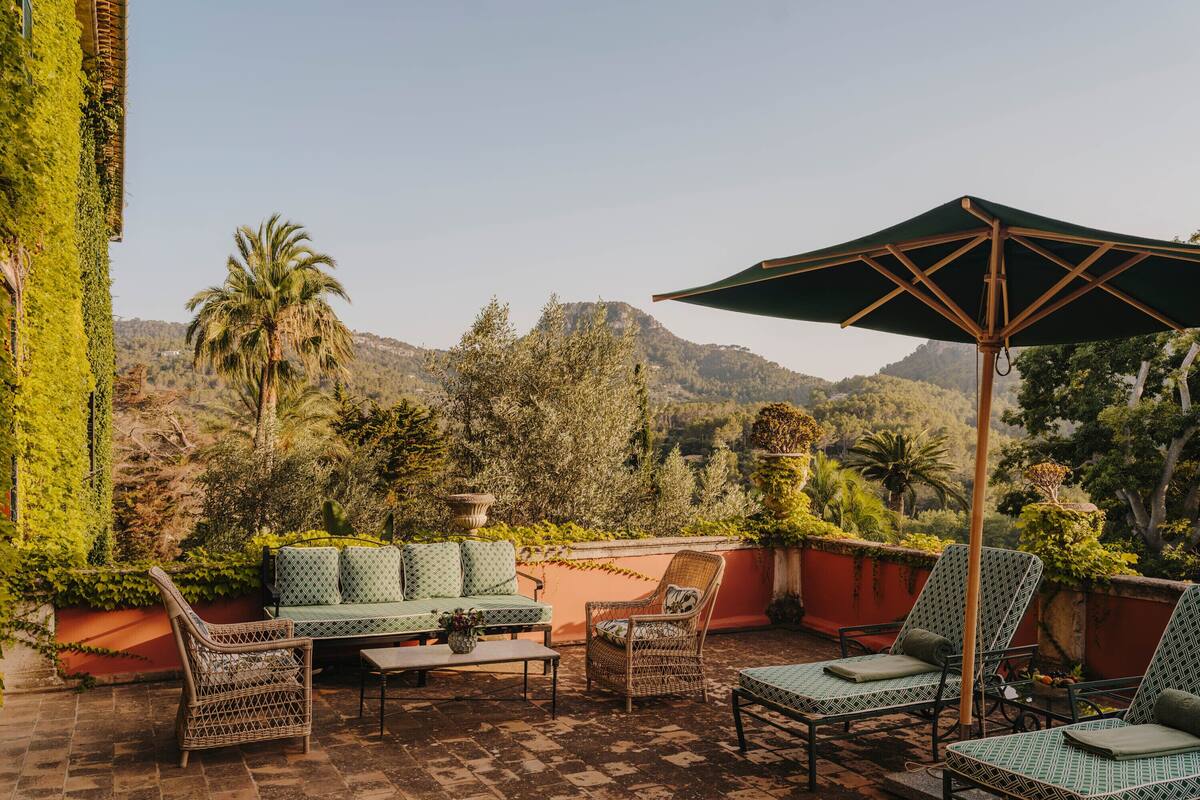 A terrace with wicker furniture, a table, and a large umbrella.