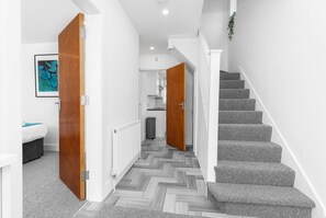 A hallway with a herringbone floor, a staircase with grey carpeted steps, and wooden doors. - 5 Bed House - Parking - Near Birmingham Centre (Birmingham)