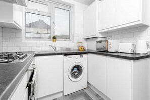 Een moderne keuken met een ingebouwde wasmachine, een fornuis en een broodrooster.