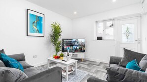 Una sala de estar moderna con sofás grises, una mesa de centro blanca y un televisor de pantalla plana.
